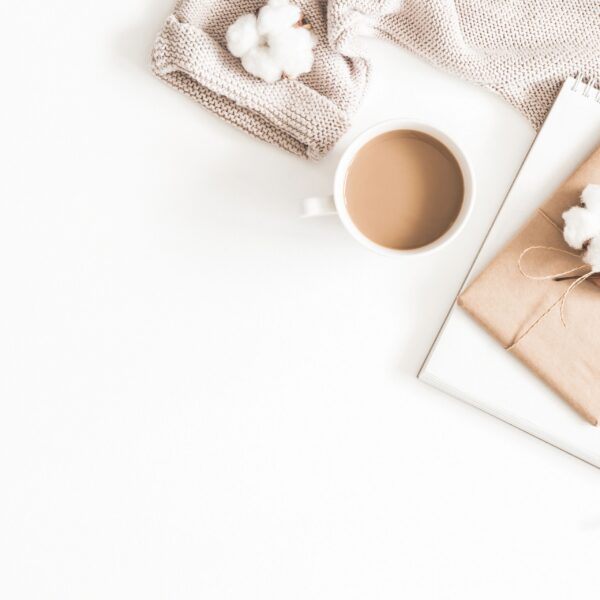 Autumn or winter composition. Cup of coffee, gift, dried autumn leaves, beige sweater on white background. Flat lay, top view