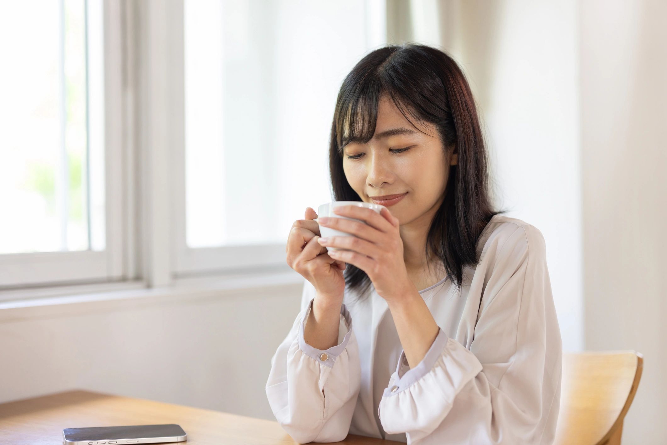 Woman enjoying coffee by a window in a calm morning setting